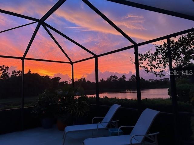 patio terrace at dusk featuring a lanai and a water view