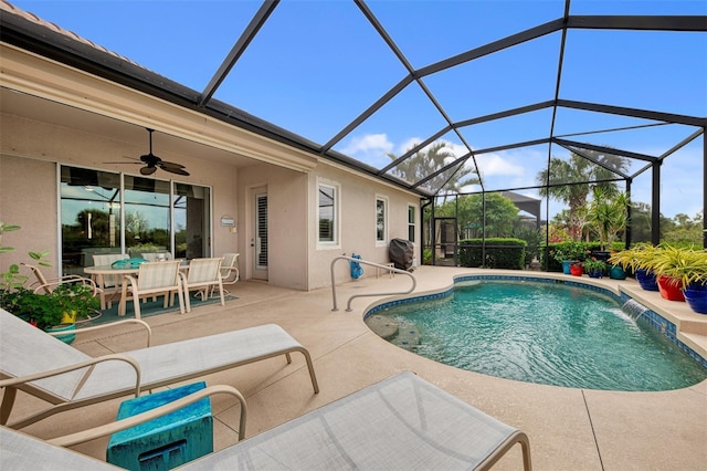 view of swimming pool featuring ceiling fan, a patio area, pool water feature, and glass enclosure