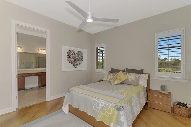 bedroom with baseboards, ceiling fan, light wood finished floors, and ensuite bath