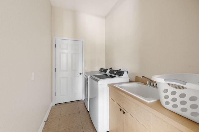 washroom with a sink, cabinet space, separate washer and dryer, light tile patterned floors, and baseboards