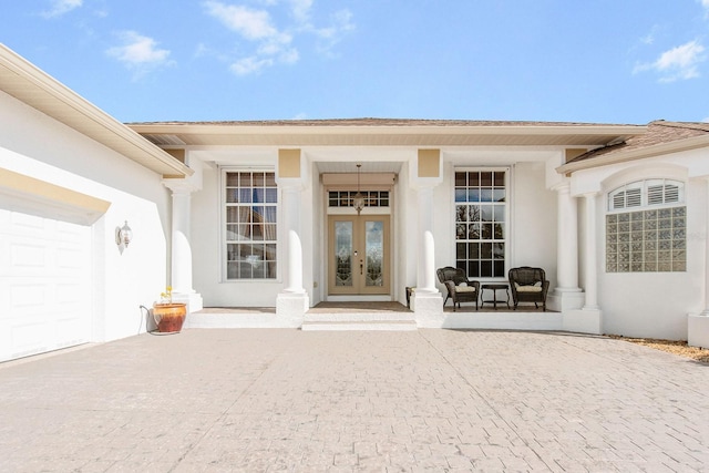 property entrance with french doors, a garage, and stucco siding