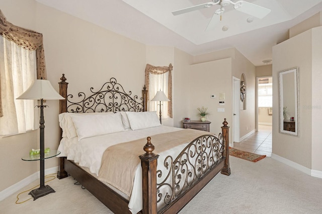 bedroom featuring ceiling fan, baseboards, a tray ceiling, and carpet
