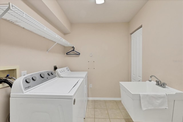 clothes washing area featuring independent washer and dryer, sink, and light tile patterned floors