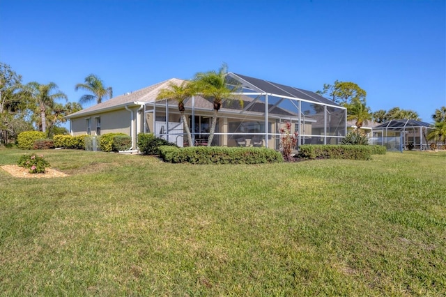 back of house with glass enclosure and a yard