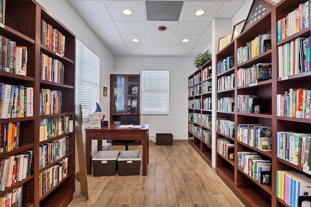 home office with a paneled ceiling and light hardwood / wood-style flooring