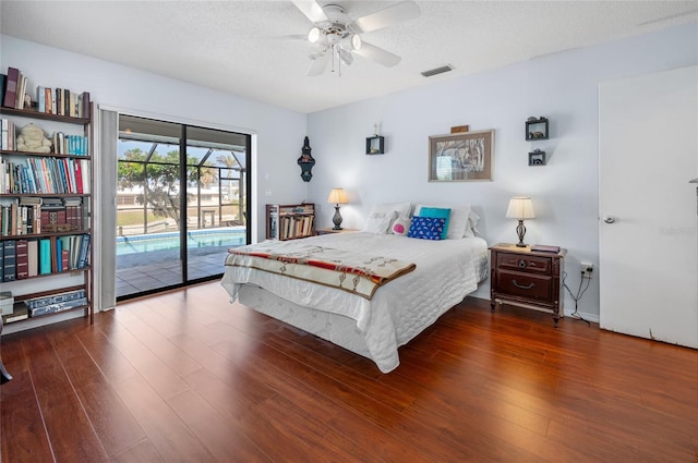 bedroom with ceiling fan, dark hardwood / wood-style flooring, a textured ceiling, and access to outside