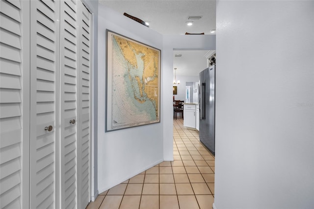 hall with a textured ceiling and light tile patterned flooring