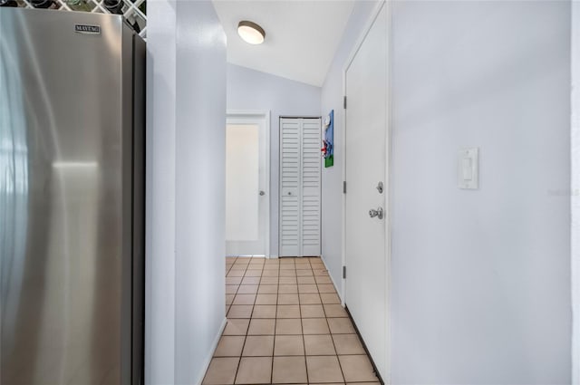 corridor featuring light tile patterned floors and lofted ceiling