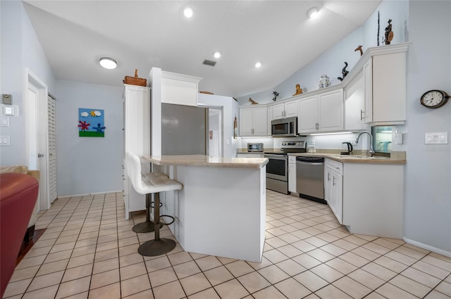 kitchen with white cabinetry, sink, lofted ceiling, a breakfast bar, and appliances with stainless steel finishes