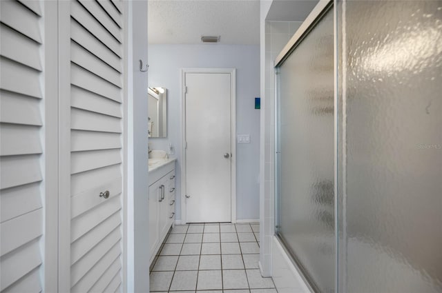 bathroom featuring a textured ceiling, vanity, tile patterned floors, and bath / shower combo with glass door