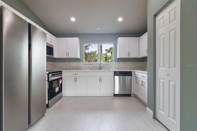 kitchen with white cabinets, decorative backsplash, sink, and stainless steel appliances