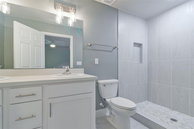 bathroom with a tile shower, vanity, and toilet