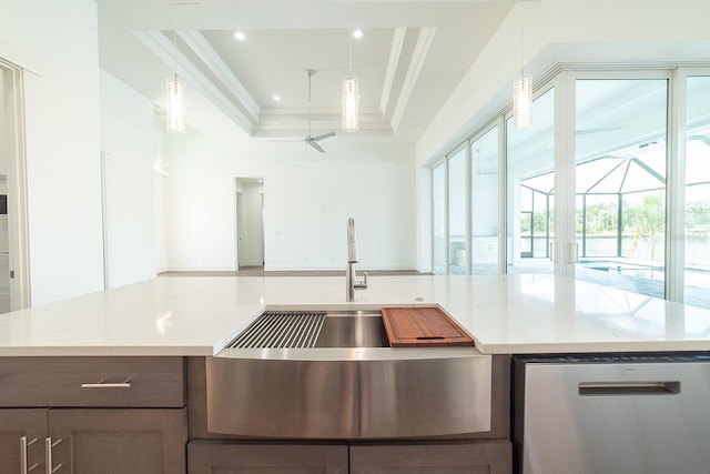 kitchen with a raised ceiling, ceiling fan, crown molding, dishwasher, and hanging light fixtures