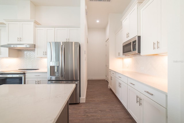 kitchen featuring backsplash, dark wood-type flooring, white cabinets, light stone counters, and stainless steel appliances