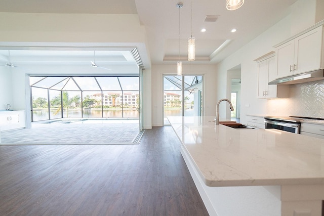 kitchen with backsplash, white cabinets, sink, light stone countertops, and decorative light fixtures