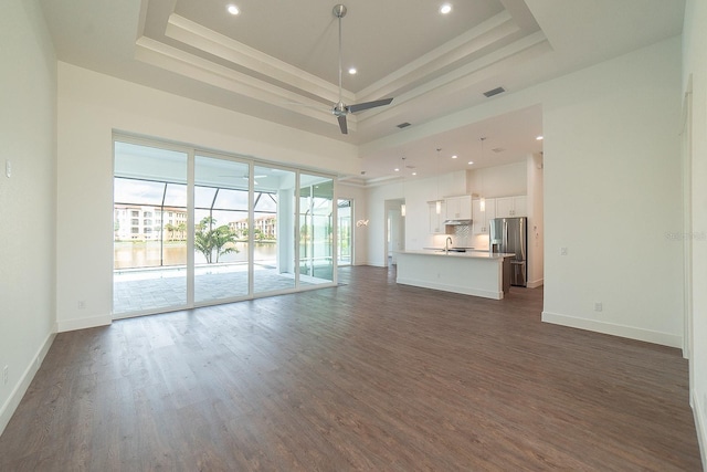 unfurnished living room featuring sink, a tray ceiling, ceiling fan, and dark hardwood / wood-style floors