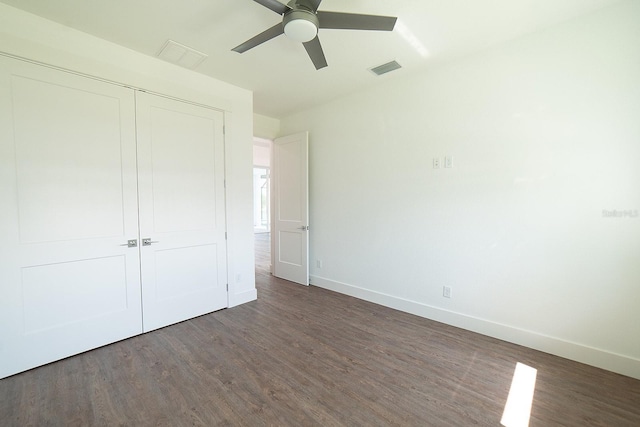 unfurnished bedroom featuring dark hardwood / wood-style flooring, ceiling fan, and a closet