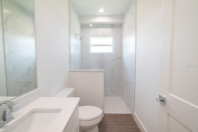 bathroom featuring vanity, toilet, wood-type flooring, and tiled shower