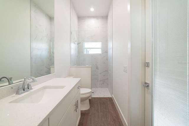 bathroom with vanity, toilet, wood-type flooring, and tiled shower