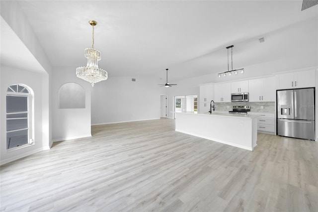 kitchen with appliances with stainless steel finishes, ceiling fan with notable chandelier, a kitchen island with sink, decorative light fixtures, and white cabinets