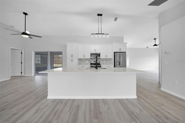 kitchen with white cabinetry, stainless steel appliances, tasteful backsplash, light hardwood / wood-style flooring, and a spacious island