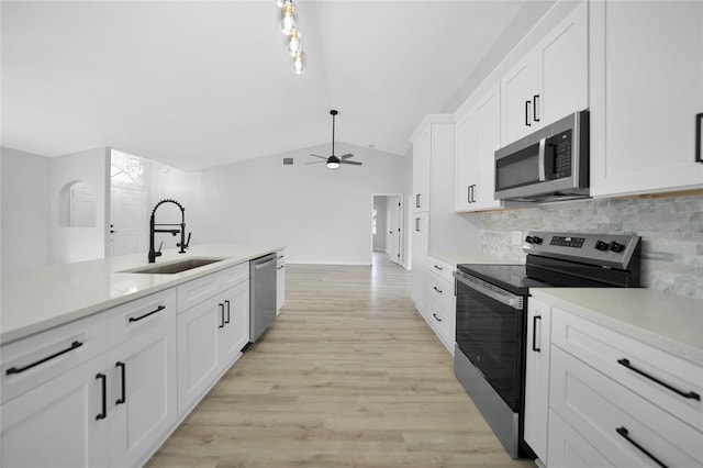 kitchen featuring white cabinets, sink, appliances with stainless steel finishes, and vaulted ceiling