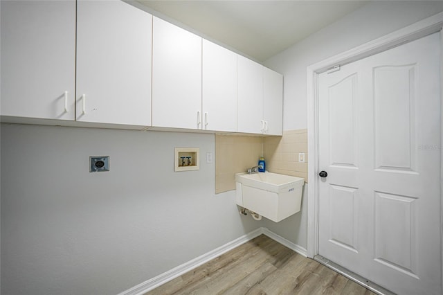 clothes washing area with electric dryer hookup, cabinets, sink, hookup for a washing machine, and light wood-type flooring