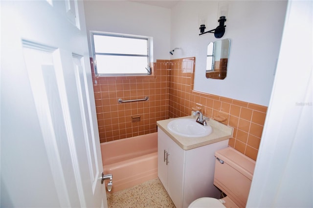 full bathroom with vanity, tiled shower / bath combo, tile walls, and toilet