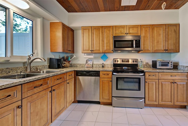 kitchen with appliances with stainless steel finishes, sink, light stone counters, and wood ceiling