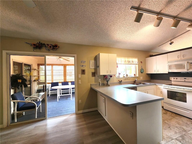 13278 Carter Ave, Port Charlotte, FL 33981 - kitchen featuring white appliances, a textured ceiling, white cabinetry, a peninsula, and rail lighting