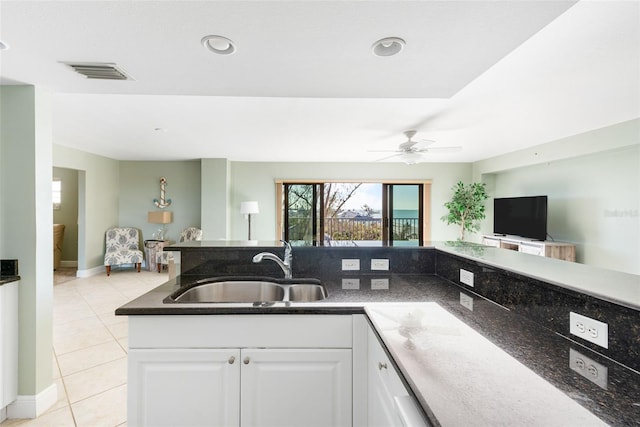 kitchen featuring light tile patterned floors, white cabinets, dark stone counters, ceiling fan, and sink