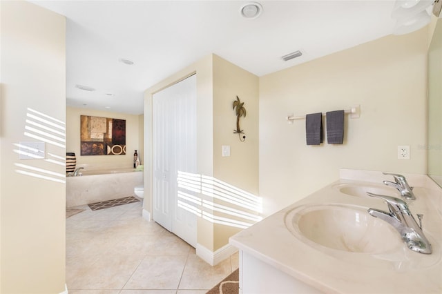 bathroom featuring a bath, vanity, tile patterned floors, and toilet