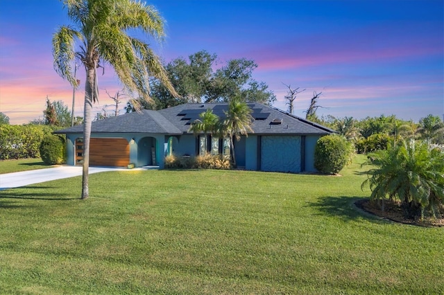 view of front of property featuring a yard, driveway, a garage, and stucco siding