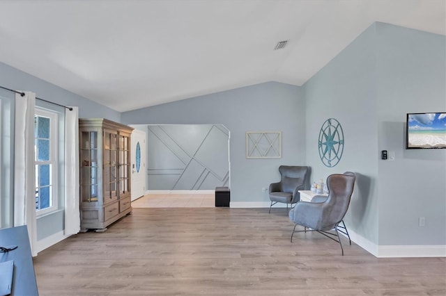 living area featuring vaulted ceiling, visible vents, light wood-style flooring, and baseboards