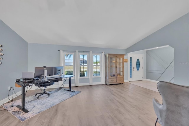 office space with light wood-style floors, vaulted ceiling, and baseboards