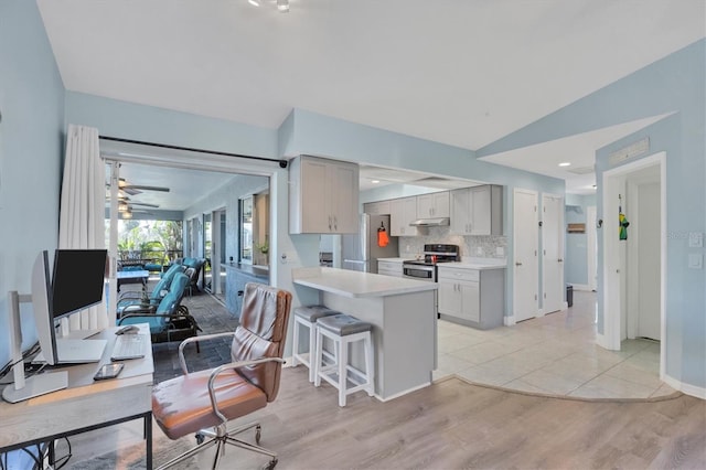 kitchen with under cabinet range hood, open floor plan, light countertops, appliances with stainless steel finishes, and vaulted ceiling