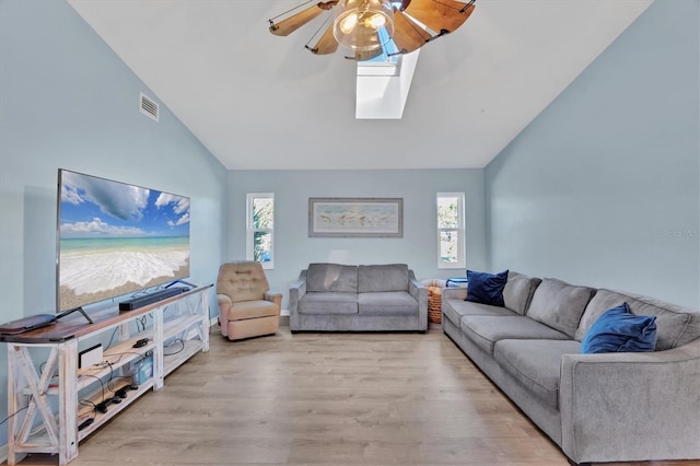 living room with a skylight, visible vents, light wood-style flooring, ceiling fan, and high vaulted ceiling