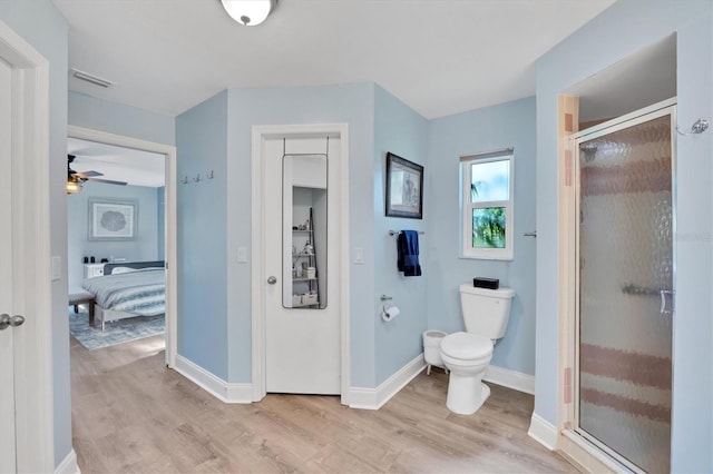 ensuite bathroom with toilet, a shower stall, ensuite bath, wood finished floors, and baseboards