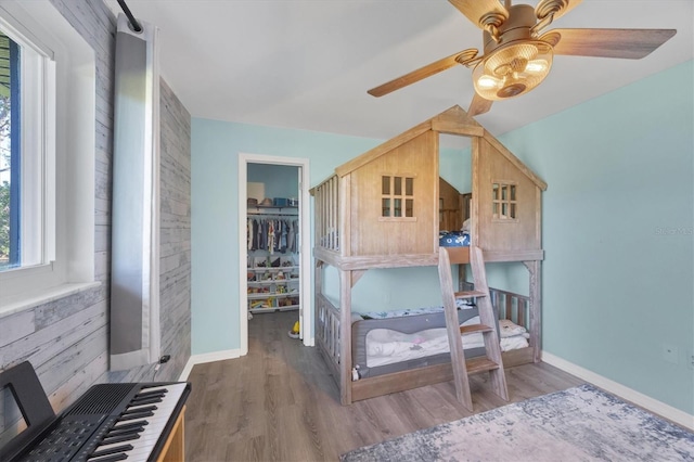 bedroom with dark wood-style floors, a closet, a walk in closet, and baseboards