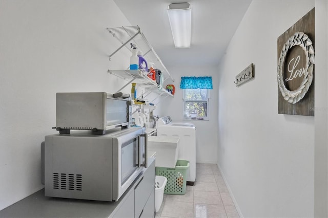 clothes washing area featuring laundry area, light tile patterned floors, baseboards, and separate washer and dryer