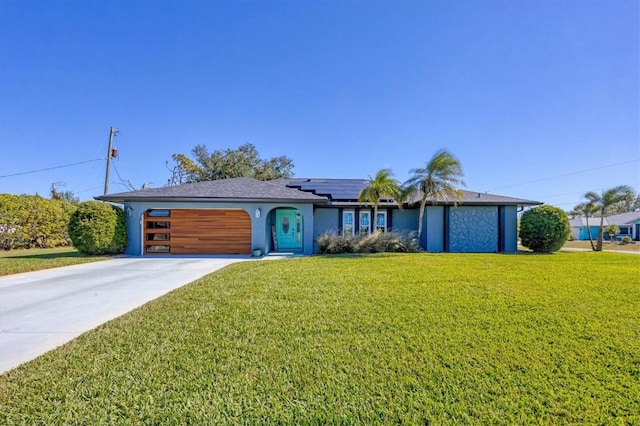 view of front of property with a garage, concrete driveway, solar panels, a front yard, and stucco siding