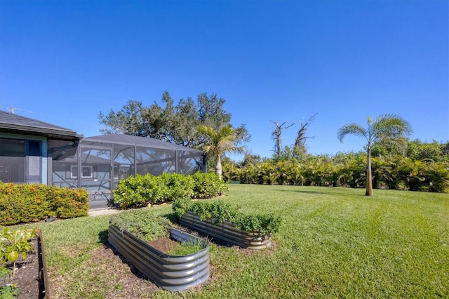 view of yard featuring a lanai and a vegetable garden