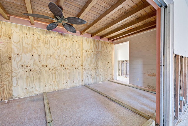 carpeted empty room featuring beamed ceiling, ceiling fan, wooden ceiling, and wooden walls