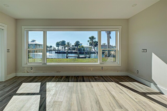 spare room with a water view, a healthy amount of sunlight, and hardwood / wood-style floors