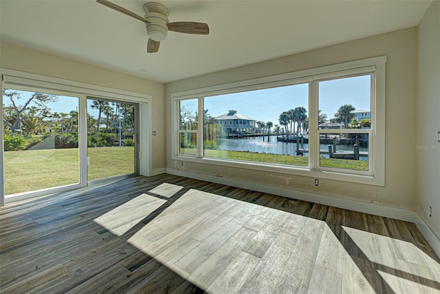 unfurnished sunroom featuring a water view, ceiling fan, and a healthy amount of sunlight