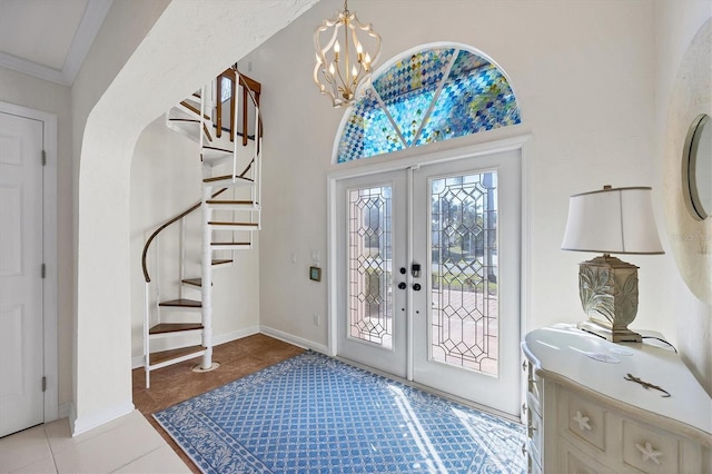 tiled entrance foyer featuring crown molding, french doors, and a chandelier