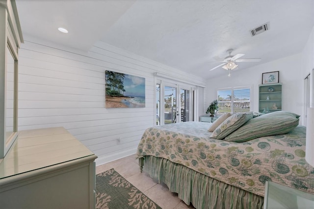 tiled bedroom with access to outside, ceiling fan, wooden walls, and vaulted ceiling