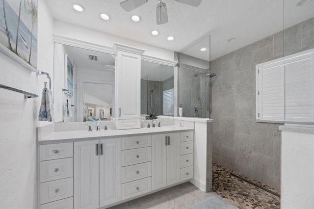 bathroom with tiled shower, vanity, and ceiling fan