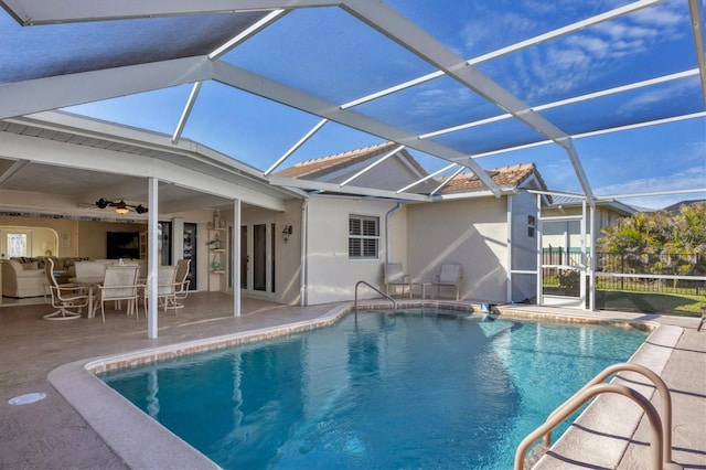 view of swimming pool with ceiling fan, a patio area, and glass enclosure