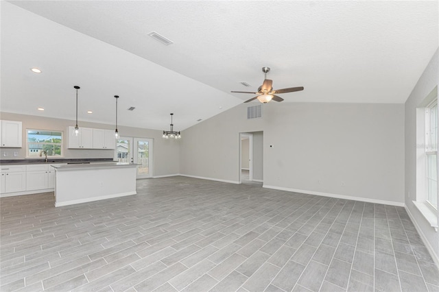 unfurnished living room with ceiling fan, vaulted ceiling, and sink